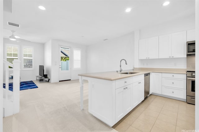 kitchen featuring a sink, white cabinetry, a peninsula, appliances with stainless steel finishes, and recessed lighting