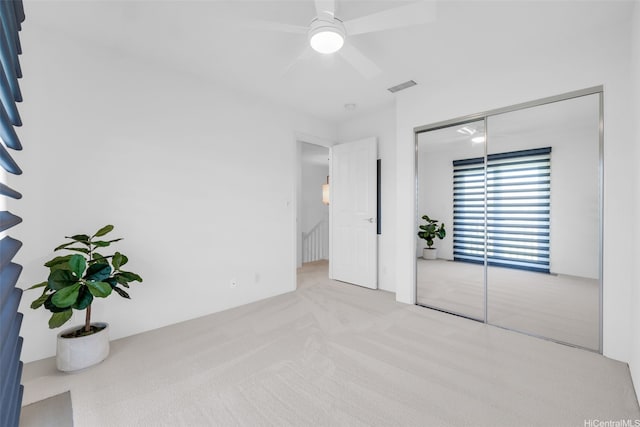 unfurnished bedroom with ceiling fan, a closet, visible vents, and carpet