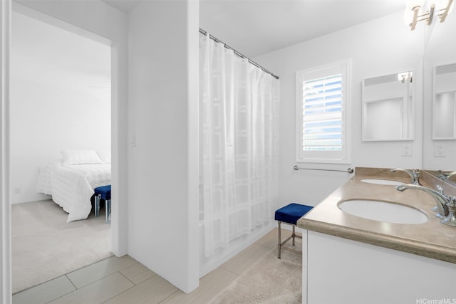 ensuite bathroom featuring double vanity, connected bathroom, and a sink