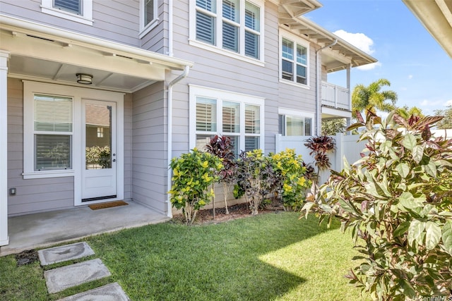 view of exterior entry with fence and a yard
