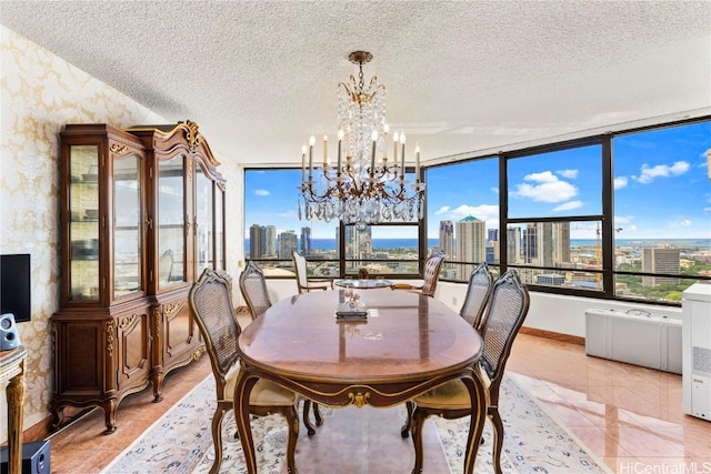 dining space featuring a textured ceiling, a view of city, a notable chandelier, and wallpapered walls