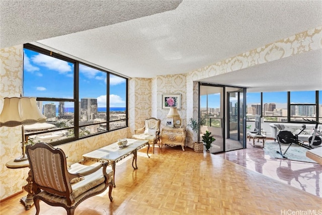 living area featuring a view of city, a textured ceiling, and wallpapered walls