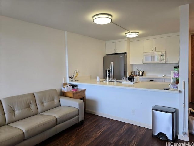 kitchen with white cabinetry, stainless steel refrigerator with ice dispenser, dark hardwood / wood-style flooring, and kitchen peninsula