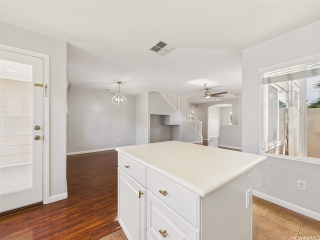 kitchen featuring visible vents, baseboards, white cabinetry, wood finished floors, and a kitchen island