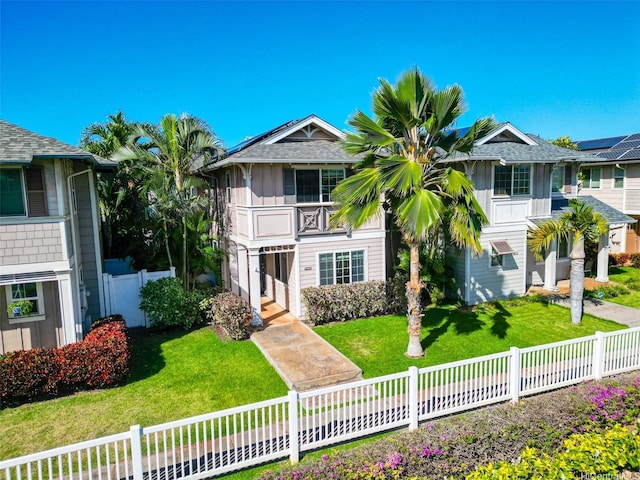 view of front of house featuring a fenced backyard, a front lawn, and a balcony