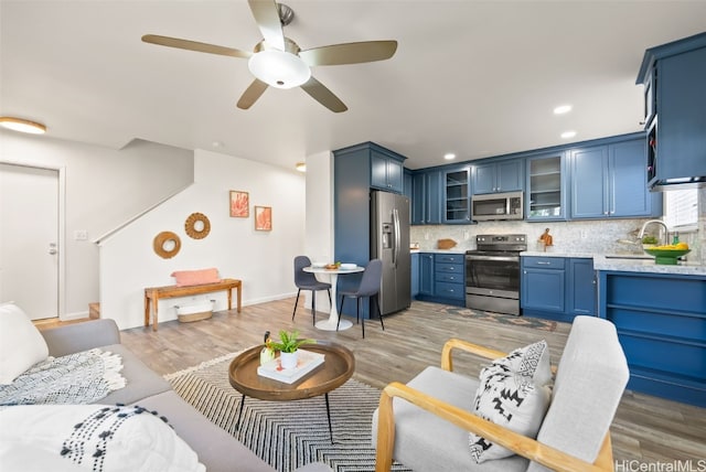 living room featuring ceiling fan, sink, and light wood-type flooring