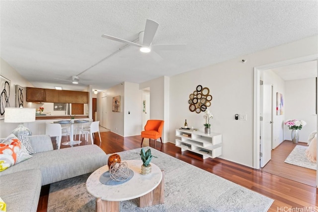 living area featuring a textured ceiling, a ceiling fan, and wood finished floors