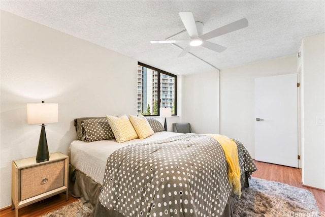 bedroom featuring a textured ceiling, ceiling fan, and wood finished floors