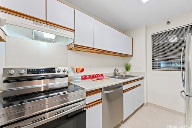 kitchen with light countertops, appliances with stainless steel finishes, white cabinetry, a sink, and under cabinet range hood