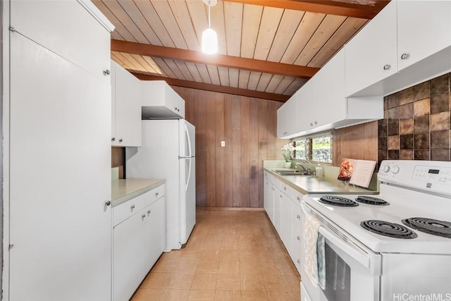 kitchen with sink, white appliances, white cabinetry, wooden walls, and beamed ceiling