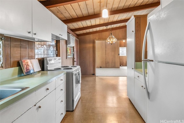 kitchen with wooden walls, lofted ceiling with beams, white cabinetry, hanging light fixtures, and white appliances