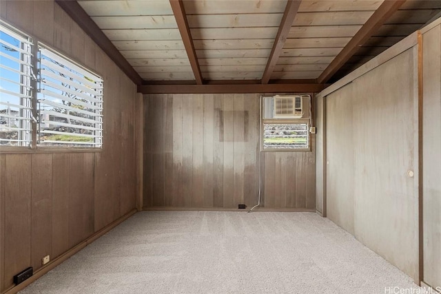 spare room featuring beamed ceiling, light colored carpet, plenty of natural light, and wooden walls