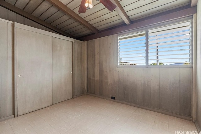 unfurnished bedroom featuring wood ceiling, lofted ceiling with beams, a closet, and wood walls