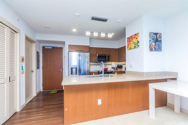 kitchen with sink, hanging light fixtures, appliances with stainless steel finishes, kitchen peninsula, and backsplash