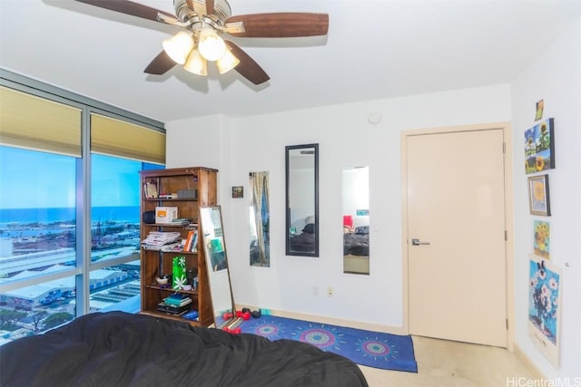 bedroom featuring ceiling fan and a wall of windows