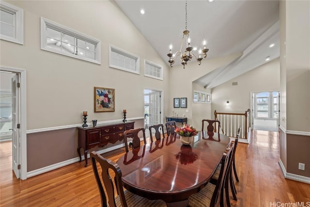 dining room featuring light hardwood / wood-style flooring, high vaulted ceiling, and an inviting chandelier