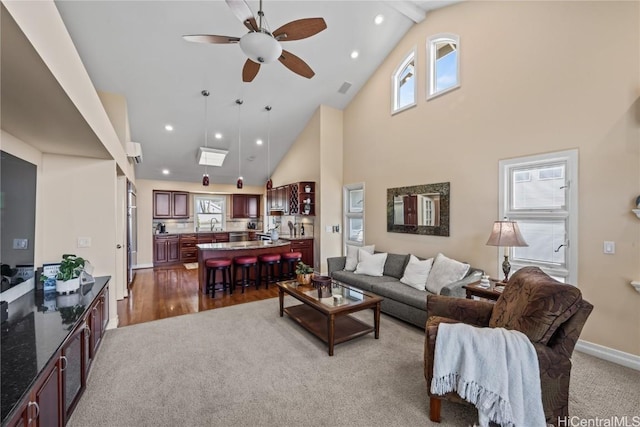 living room featuring dark carpet, plenty of natural light, high vaulted ceiling, and ceiling fan