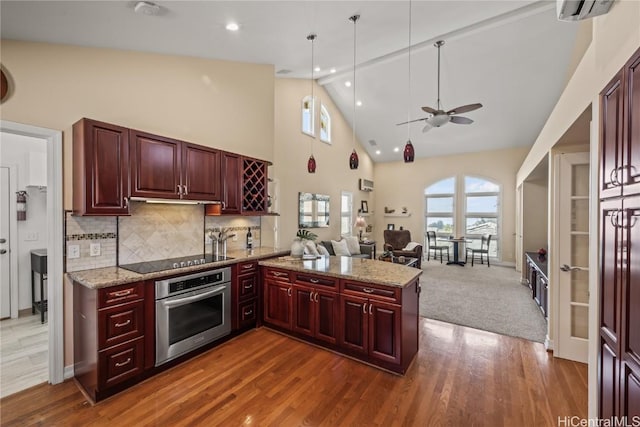 kitchen with black electric cooktop, oven, kitchen peninsula, and hardwood / wood-style floors