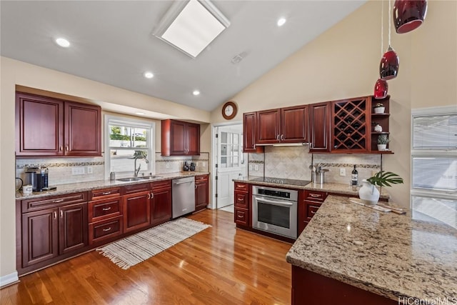 kitchen featuring light wood-type flooring, sink, light stone counters, appliances with stainless steel finishes, and decorative backsplash