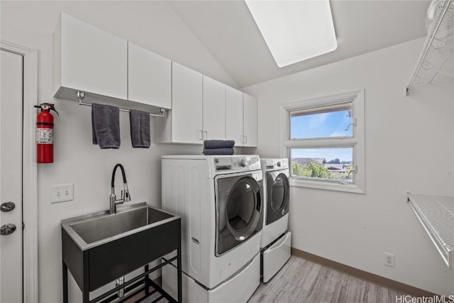 laundry room featuring washer and dryer, cabinets, sink, and light hardwood / wood-style flooring