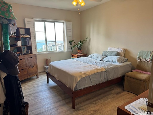 bedroom with hardwood / wood-style floors and a water view