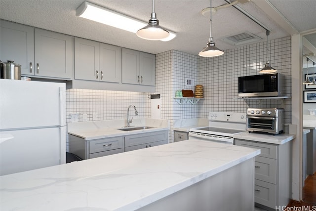 kitchen with gray cabinets, pendant lighting, sink, light stone countertops, and white appliances