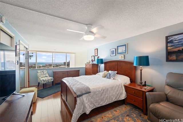 bedroom with hardwood / wood-style flooring, ceiling fan, and a textured ceiling