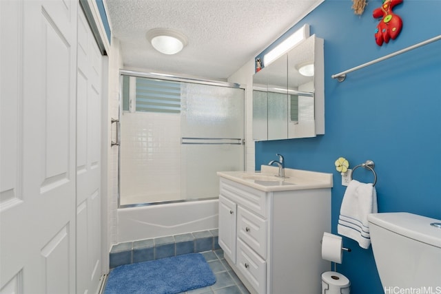 full bathroom featuring toilet, bath / shower combo with glass door, a textured ceiling, vanity, and tile patterned flooring