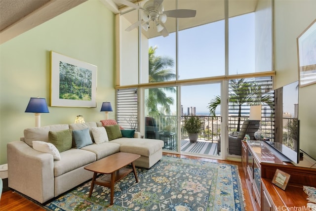 living room with expansive windows, wood-type flooring, a high ceiling, and ceiling fan