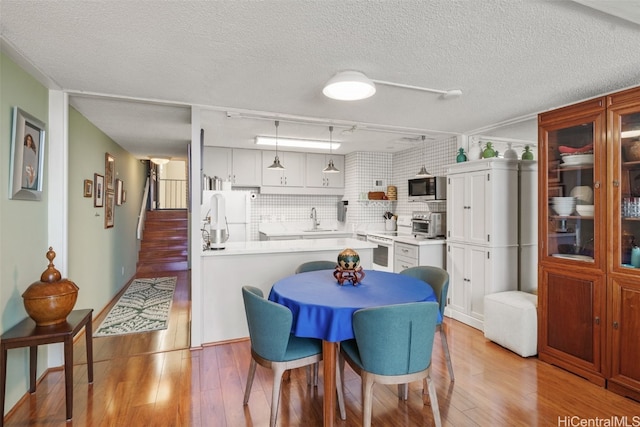 dining room with sink, a textured ceiling, and light hardwood / wood-style floors