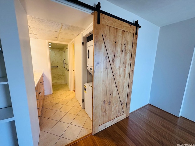 1600 Ala Moana Blvd Unit 3202, Honolulu, HI 96814 - hall with a barn door, light wood-style flooring, stacked washer / dryer, and a paneled ceiling