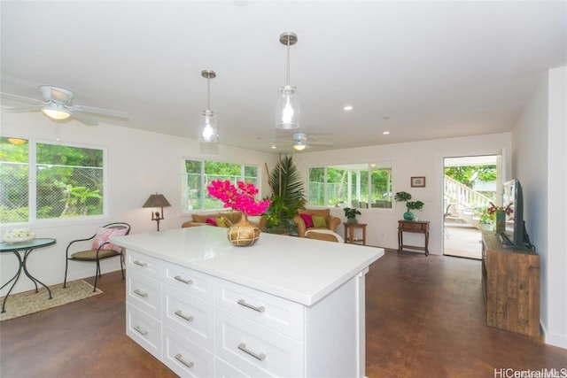 kitchen featuring hanging light fixtures, ceiling fan, white cabinets, and a kitchen island