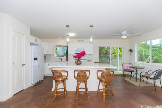 kitchen with hanging light fixtures, white cabinets, and white appliances