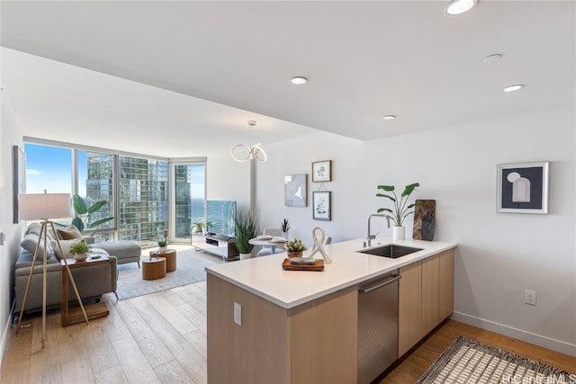 kitchen featuring a sink, open floor plan, light countertops, hanging light fixtures, and dishwasher