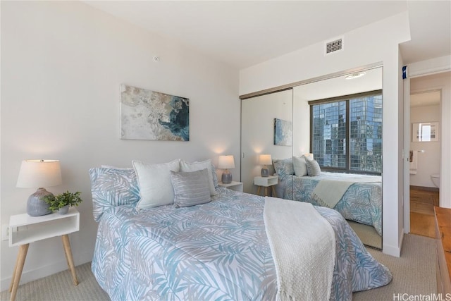 bedroom featuring a closet, visible vents, light carpet, and baseboards