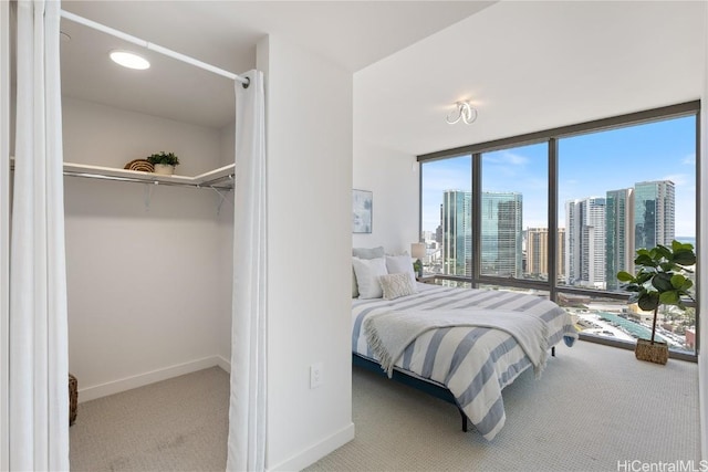 bedroom with a view of city, a wall of windows, light carpet, and baseboards