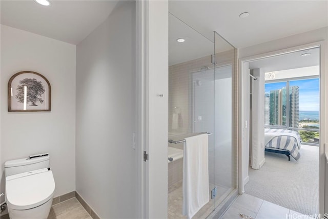 ensuite bathroom with baseboards, toilet, ensuite bathroom, tile patterned flooring, and a city view