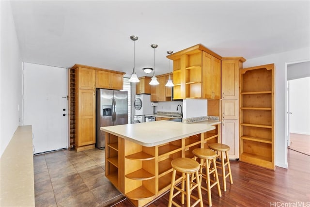 kitchen featuring refrigerator, light countertops, stainless steel refrigerator with ice dispenser, open shelves, and a sink