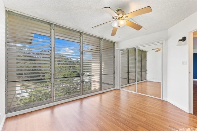 interior space featuring baseboards, a textured ceiling, a ceiling fan, and wood finished floors