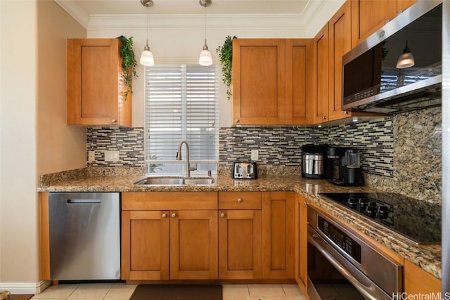 kitchen with crown molding, stainless steel appliances, brown cabinetry, a sink, and dark stone counters