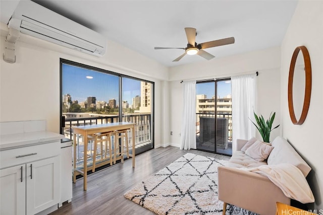 living room with ceiling fan, a wall mounted AC, and light hardwood / wood-style floors