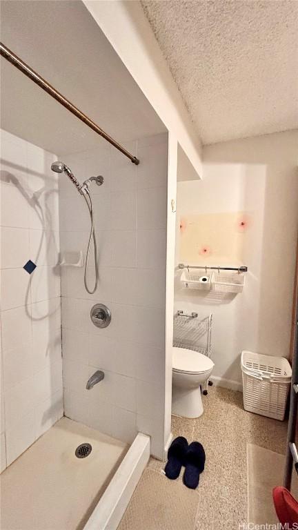 bathroom featuring a textured ceiling, a stall shower, toilet, and baseboards