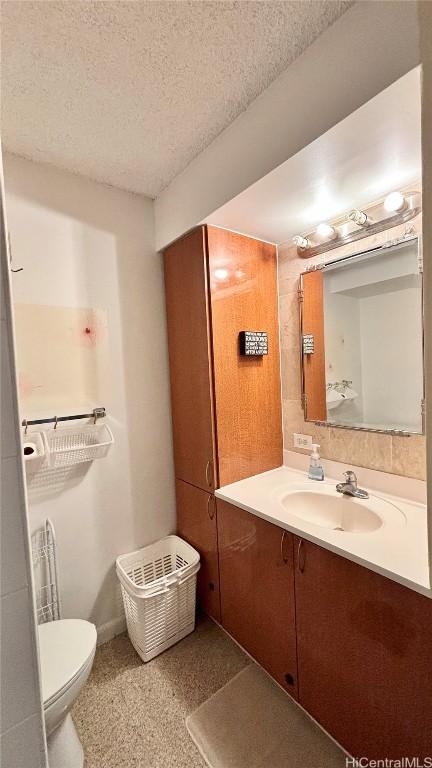 bathroom featuring toilet, a textured ceiling, and vanity