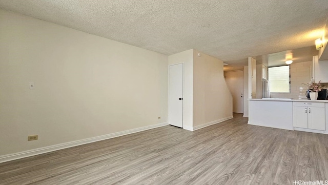 unfurnished living room featuring a textured ceiling and light wood-type flooring