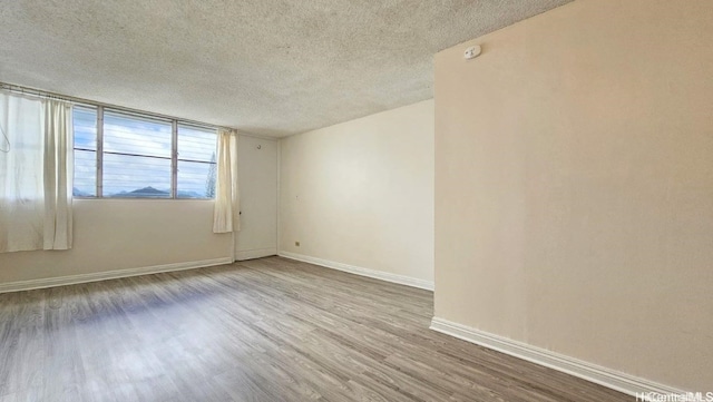 spare room featuring hardwood / wood-style flooring and a textured ceiling