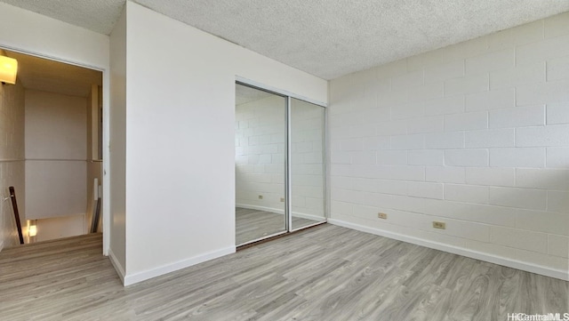 unfurnished bedroom with a textured ceiling, light wood-type flooring, and a closet