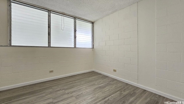 unfurnished room with hardwood / wood-style floors and a textured ceiling