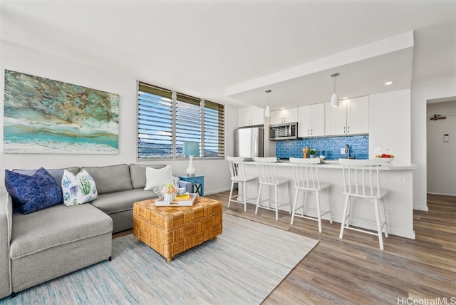 living area with light wood-type flooring, baseboards, and recessed lighting