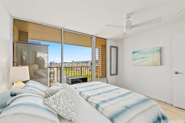 carpeted bedroom with access to exterior, ceiling fan, a wall of windows, and a city view