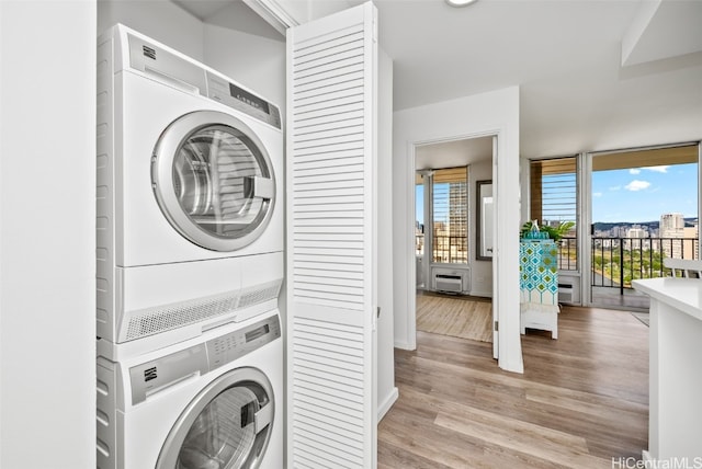 clothes washing area featuring stacked washer and dryer, laundry area, and light wood-style flooring